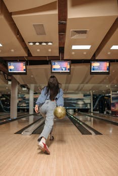 A woman engages in a lively bowling game at an indoor alley, showcasing focus and style.