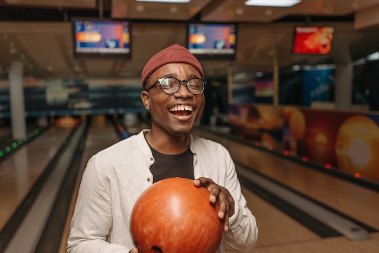 Man In White Long Sleeve Shirt Holding Orang Bowling Ball