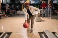 A diverse group of friends enjoys a fun game of bowling at an indoor alley.