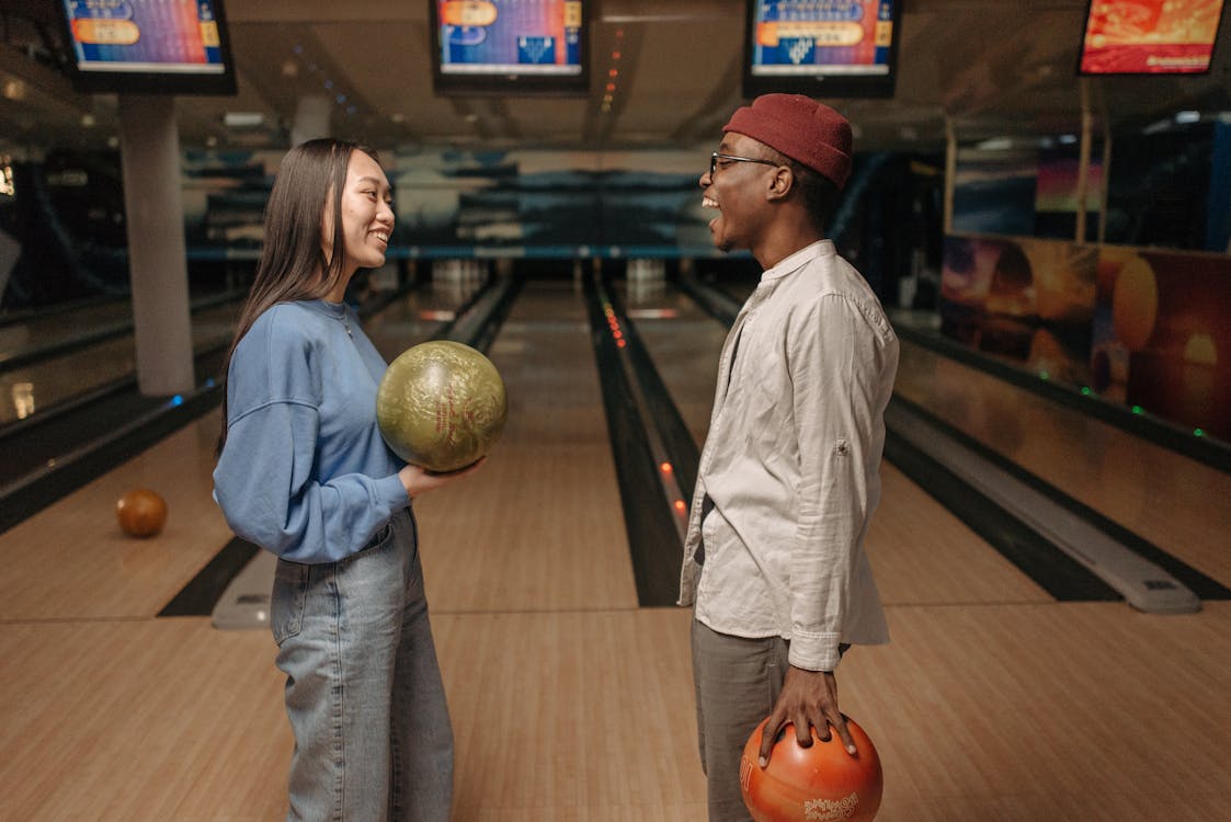 Free Man and Woman Holding Bowling Ball while Talking Stock Photo