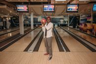 Man standing in a bowling alley holding a bowling ball, ready to play.