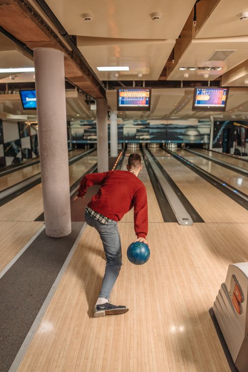 Free Man preparing to bowl at a modern indoor bowling alley with a striking blue ball. Stock Photo
