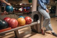 Two friends enjoying a fun bowling night with colorful bowling balls indoors.