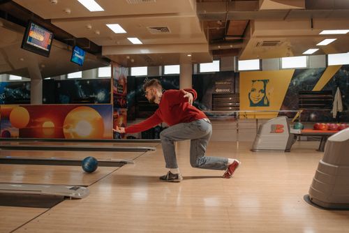 Free Adult man in casual wear bowling in a vibrant indoor alley with colorful decor. Stock Photo