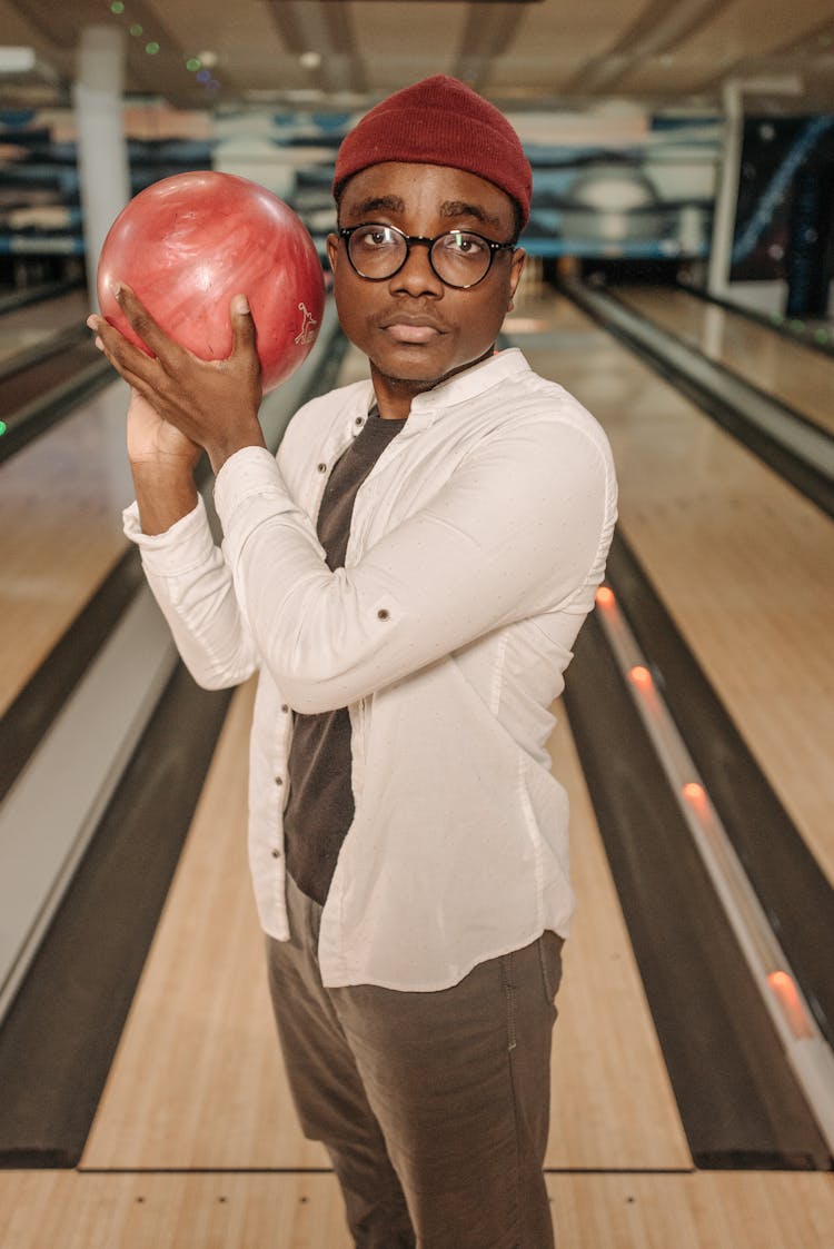 Man In White Long Sleeve Shirt Holding Red Bowling Ball