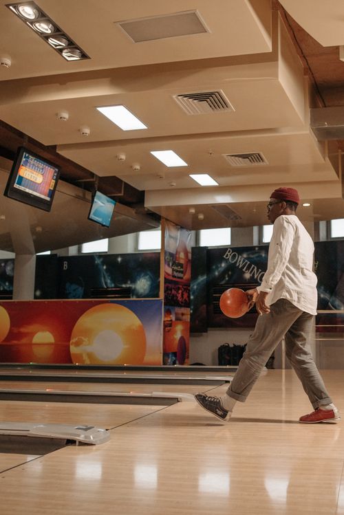 Free A man preparing to bowl at a brightly lit alley, showcasing modern leisure and fun activity. Stock Photo