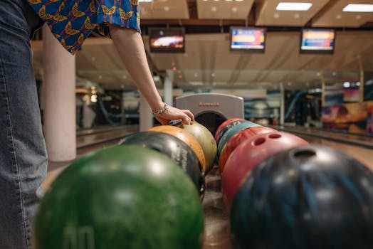 A person selecting a bowling ball at an indoor bowling alley. Perfect for leisure and sports concepts.