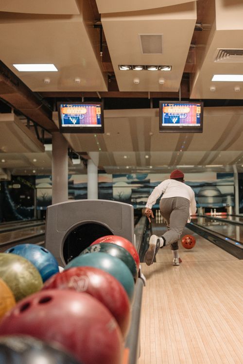 Free A person throws a bowling ball down the lane in a modern bowling alley with colorful balls. Stock Photo