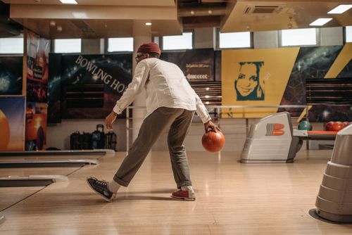 Free Side view of a man bowling in an indoor alley showcasing leisure and recreation. Stock Photo