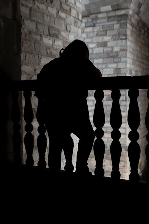Silhouette of a Person Standing on the Balcony