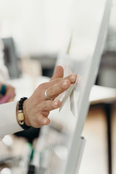 A hand interacting with a digital whiteboard in a bright office setting.