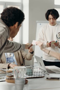 Team members exchanging ideas and materials in a collaborative business meeting.