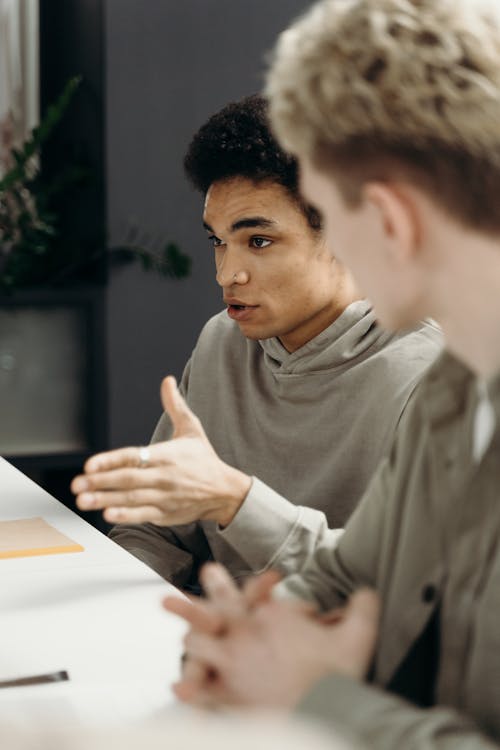 Man in Gray Hoodie Sitting at the Table