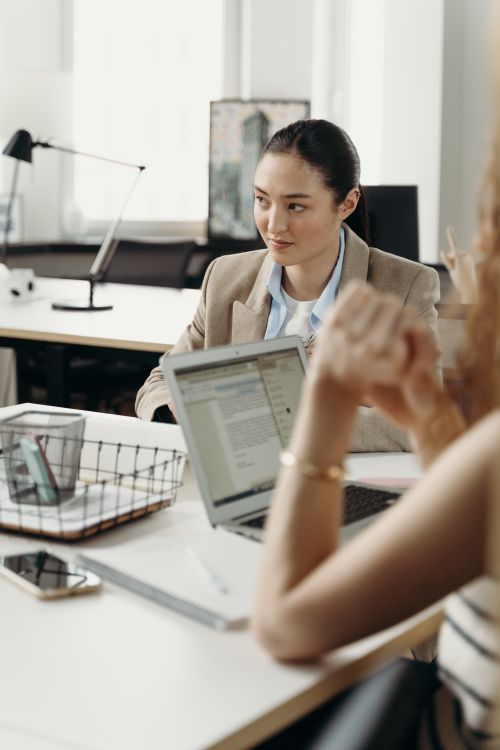 Free Businesswomen engage in a planning session in a modern office setting with laptops. Stock Photo