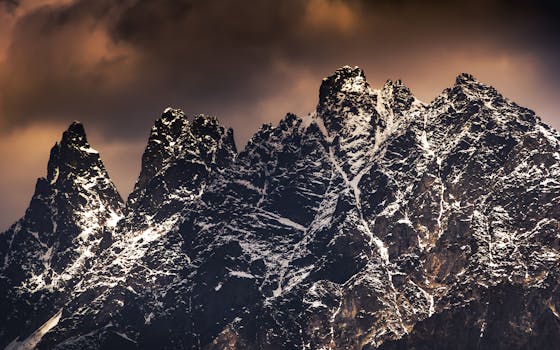 Dramatic snow-capped mountains towering under a moody sky in Mestia, Georgia.