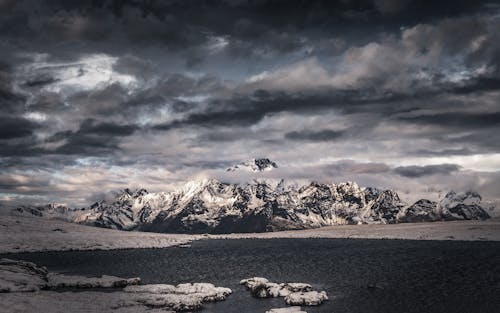 Snow Covered Rocky Mountains Under Cloudy Sky