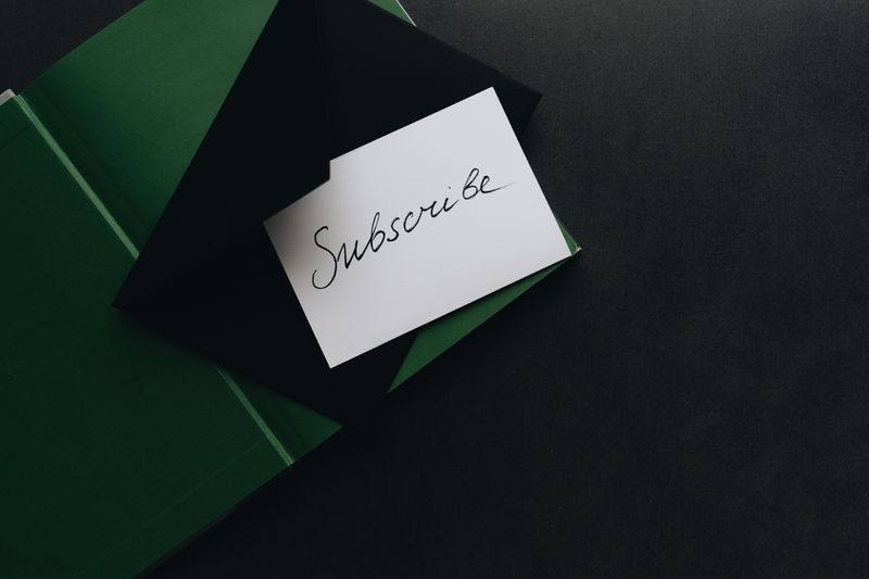 Handwritten subscribe note on a dark desk — alleksana on Pexels