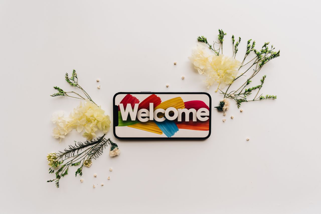 creative flat lay with a smartphone displaying a colorful welcome sign