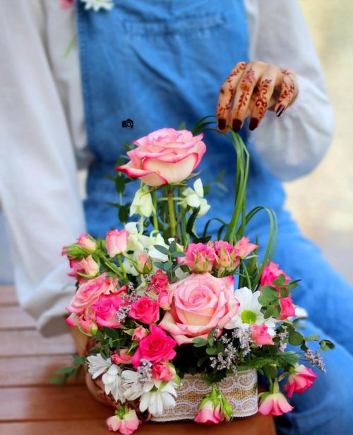 Free A vibrant floral arrangement held by a woman with intricate henna tattoos, showcasing roses and other blooms. Stock Photo