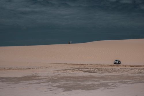 Free Jeep navigating the sandy dunes of Jericoacoara desert under a cloudy sky. Stock Photo