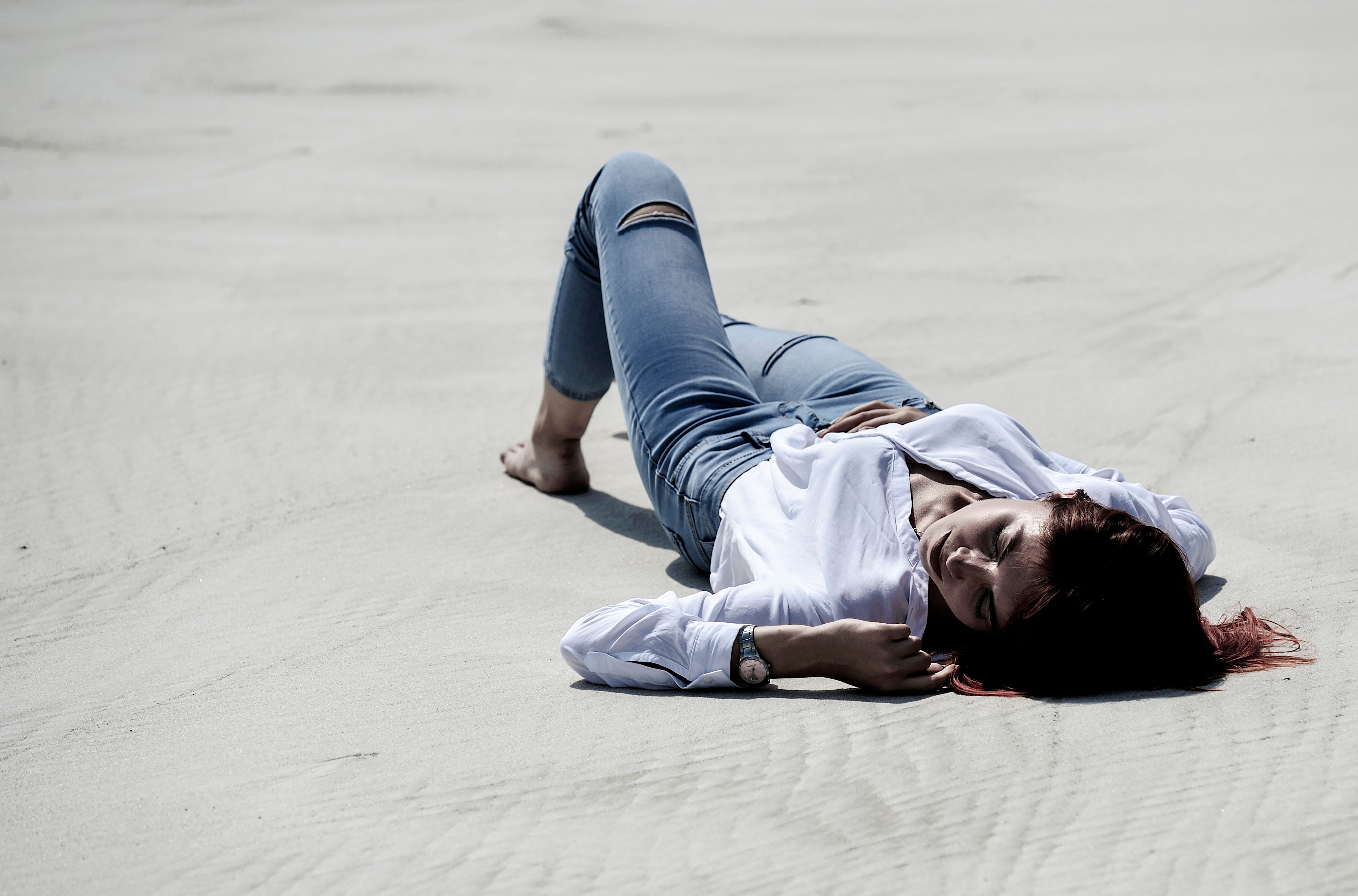 A Woman in a Dress Shirt and Ripped Jeans Lying on the Sand · Free ...