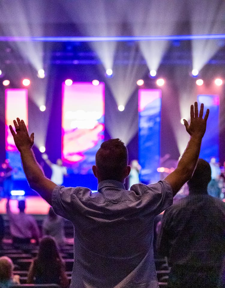 A Man Raising His Hands During A Concert