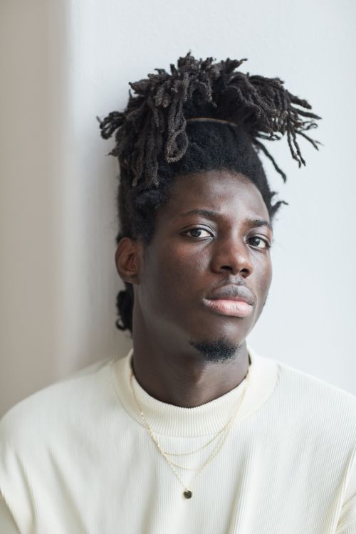 Free Close-up portrait of a man with dreadlocks wearing a white shirt, looking thoughtful. Stock Photo