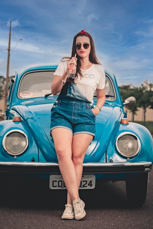 A Woman Sitting in Front of a Volkswagen Beetle