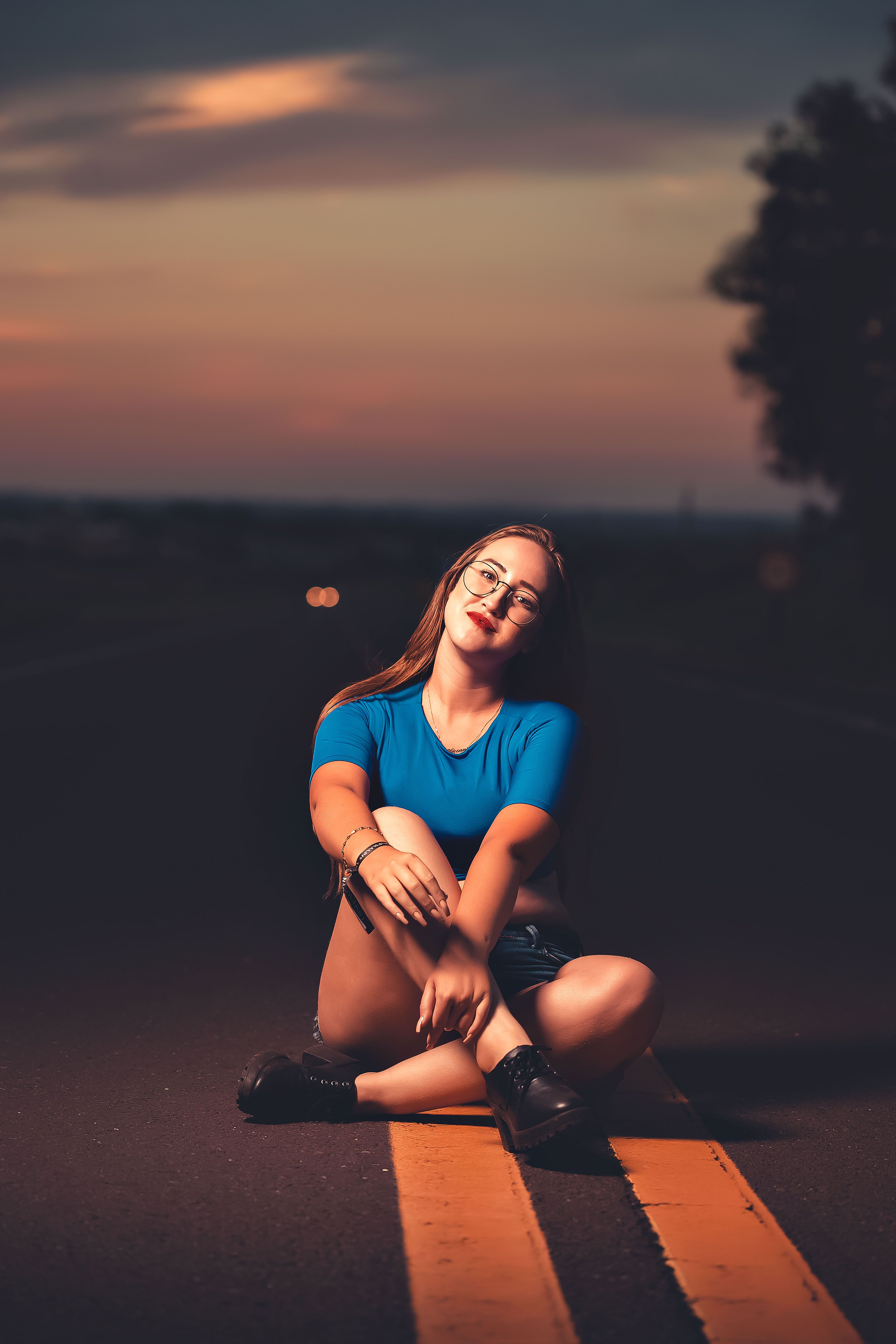 A Woman in Blue Shirt Sitting on the Road · Free Stock Photo