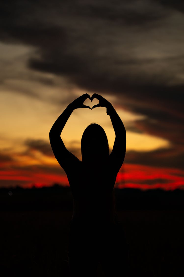 Silhouette Of A Woman Doing A Heart Shape With Her Hands