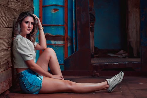 A Woman in White Shirt and Denim Shorts Sitting on the Floor