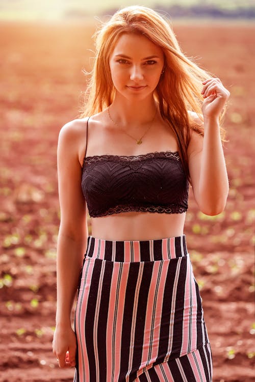 A Woman in Black Top and Striped Skirt Holding Her Hair