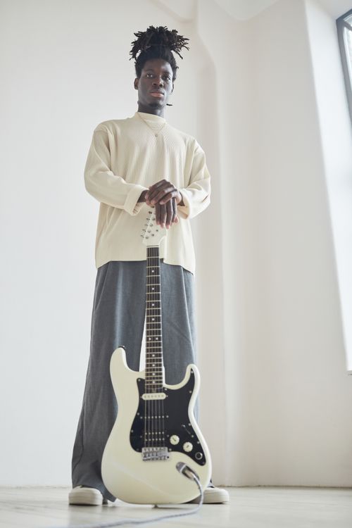 Free Stylish black man with electric guitar in bright room. Music and fashion concept. Stock Photo