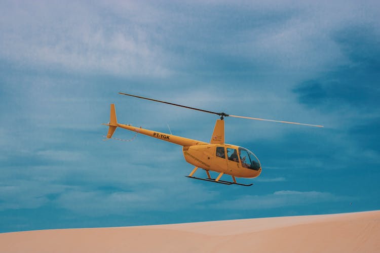 A Yellow Helicopter Flying Under Blue Sky 