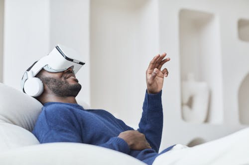Man in Blue Sweater Watching Video Through VR Headset