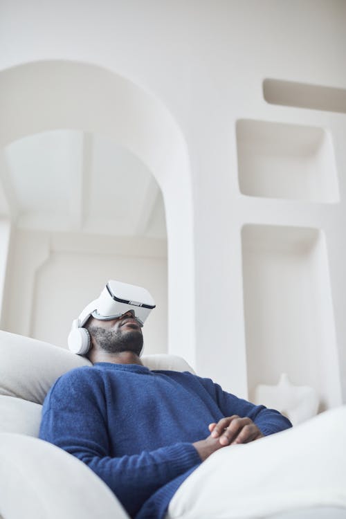 Man in Blue Sweater Watching Video Through VR Headset