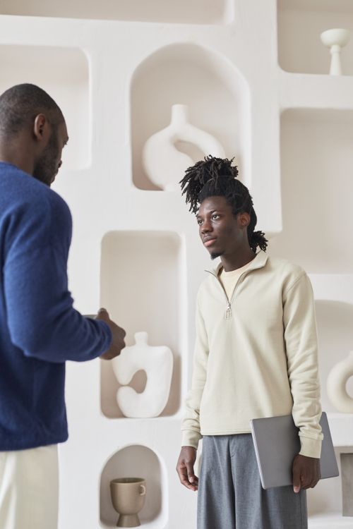 Free Two colleagues having a discussion in a contemporary office space with decorative shelves. Stock Photo
