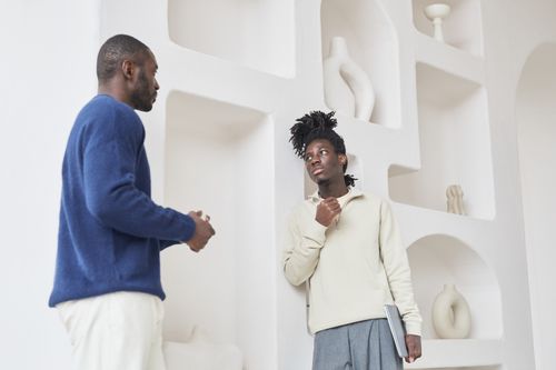 Free Two men in conversation against a modern interior backdrop, discussing ideas creatively. Stock Photo