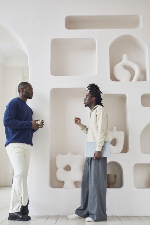 Free Two men engaged in a lively conversation in a contemporary minimalist interior with abstract decor. Stock Photo