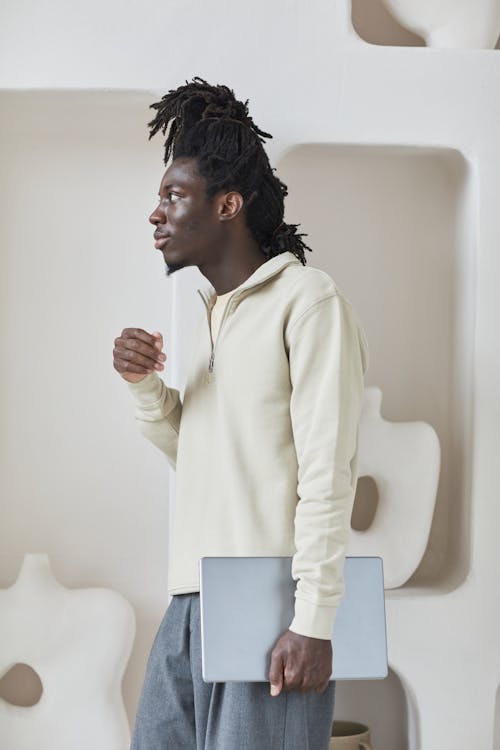 Free A Man in a Beige Sweater Holding a Laptop Stock Photo