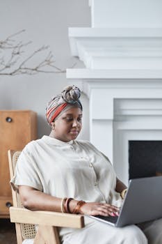 Businesswoman using laptop in cozy indoor setting, remote work lifestyle.