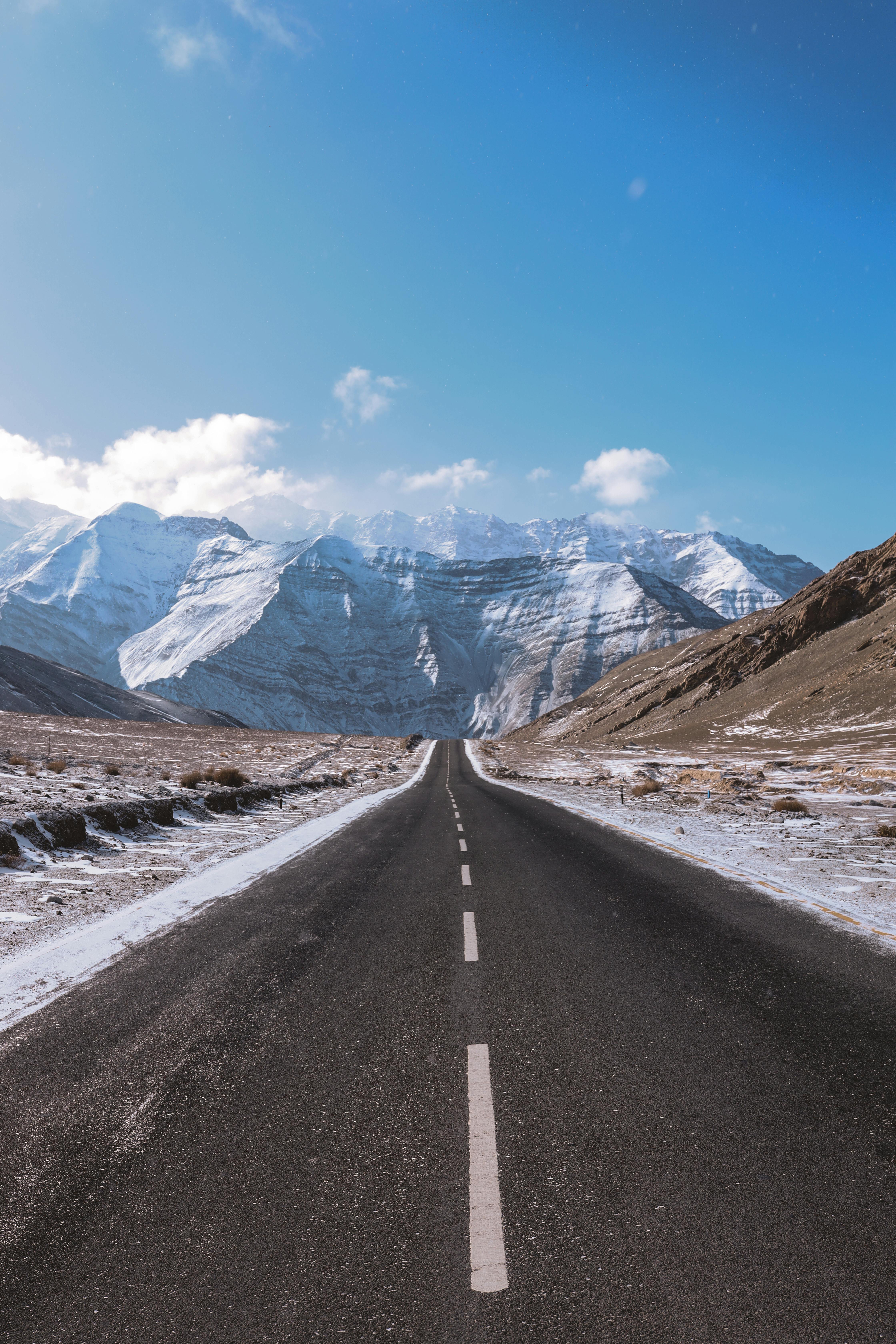 A breathtaking view of a snowy mountain highway under a clear blue sky, perfect for travel and adventure enthusiasts.