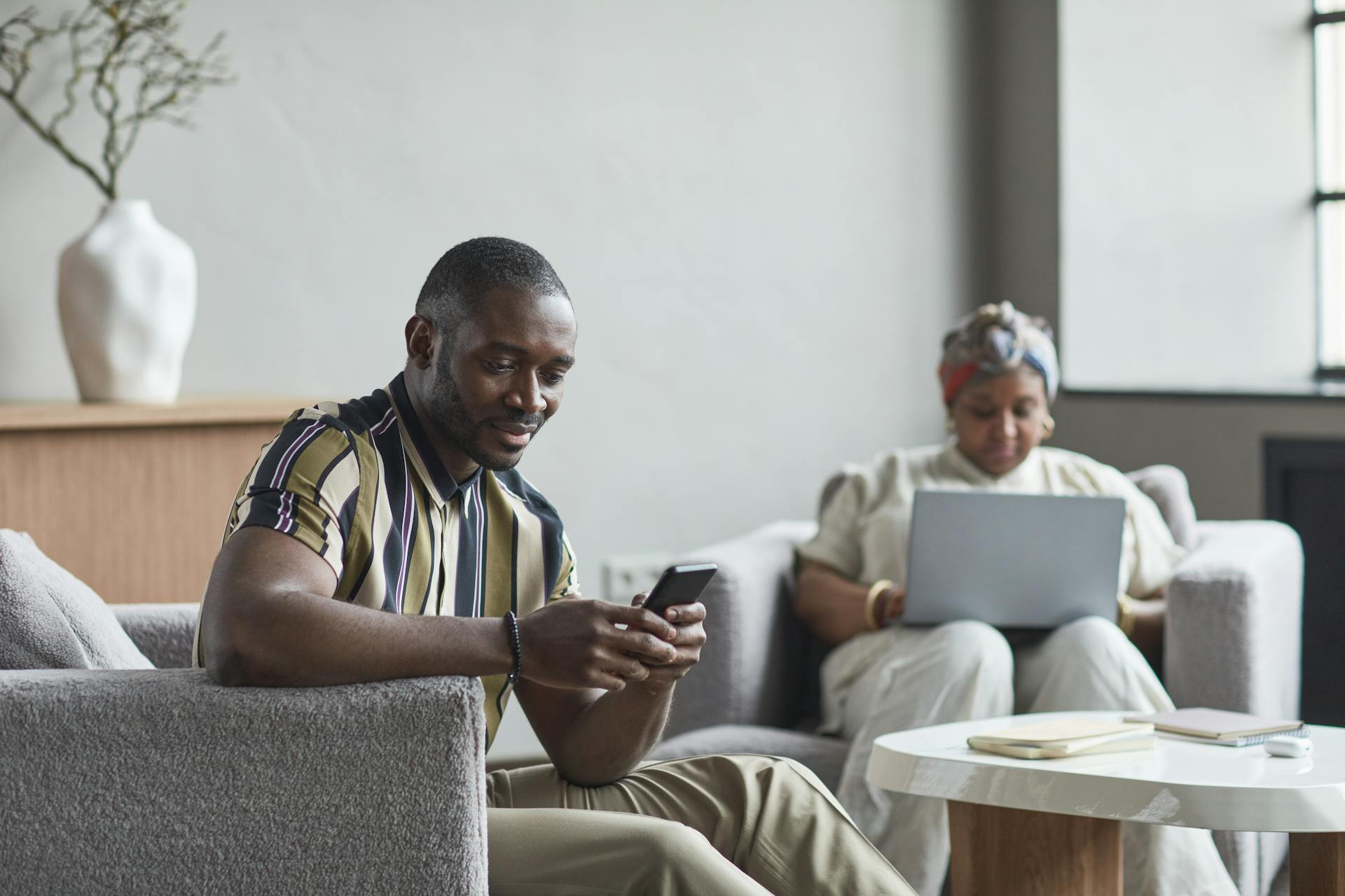 Two colleagues engaging with technology in a contemporary hotel lobby work setting.