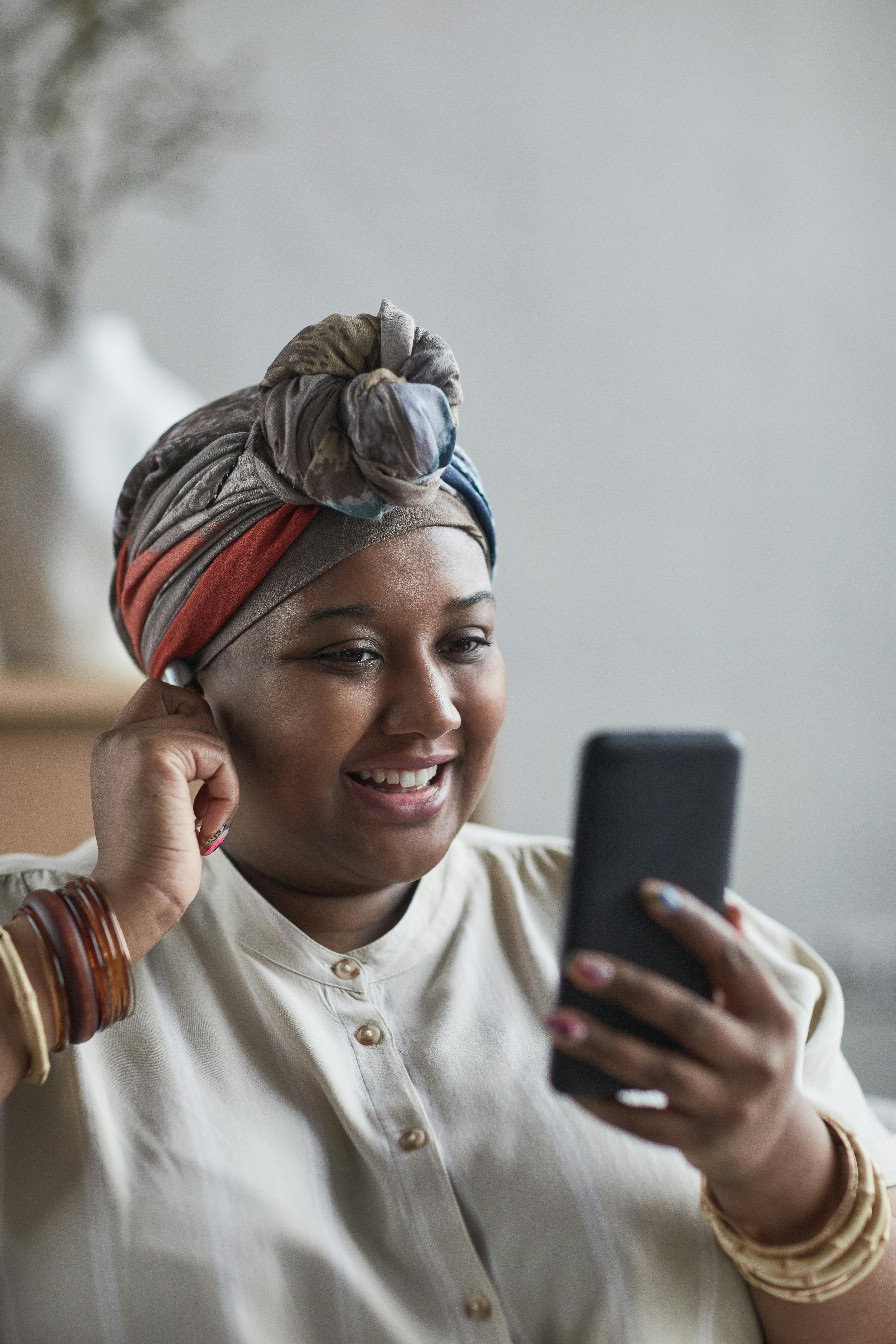 woman with a headwrap looking at her cell phone