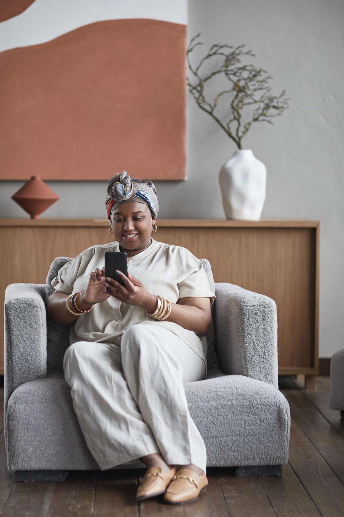 A woman in an armchair using her phone at home