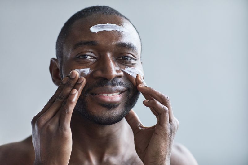 Homme appliquant un baume hydratant sur son visage apres le rasage