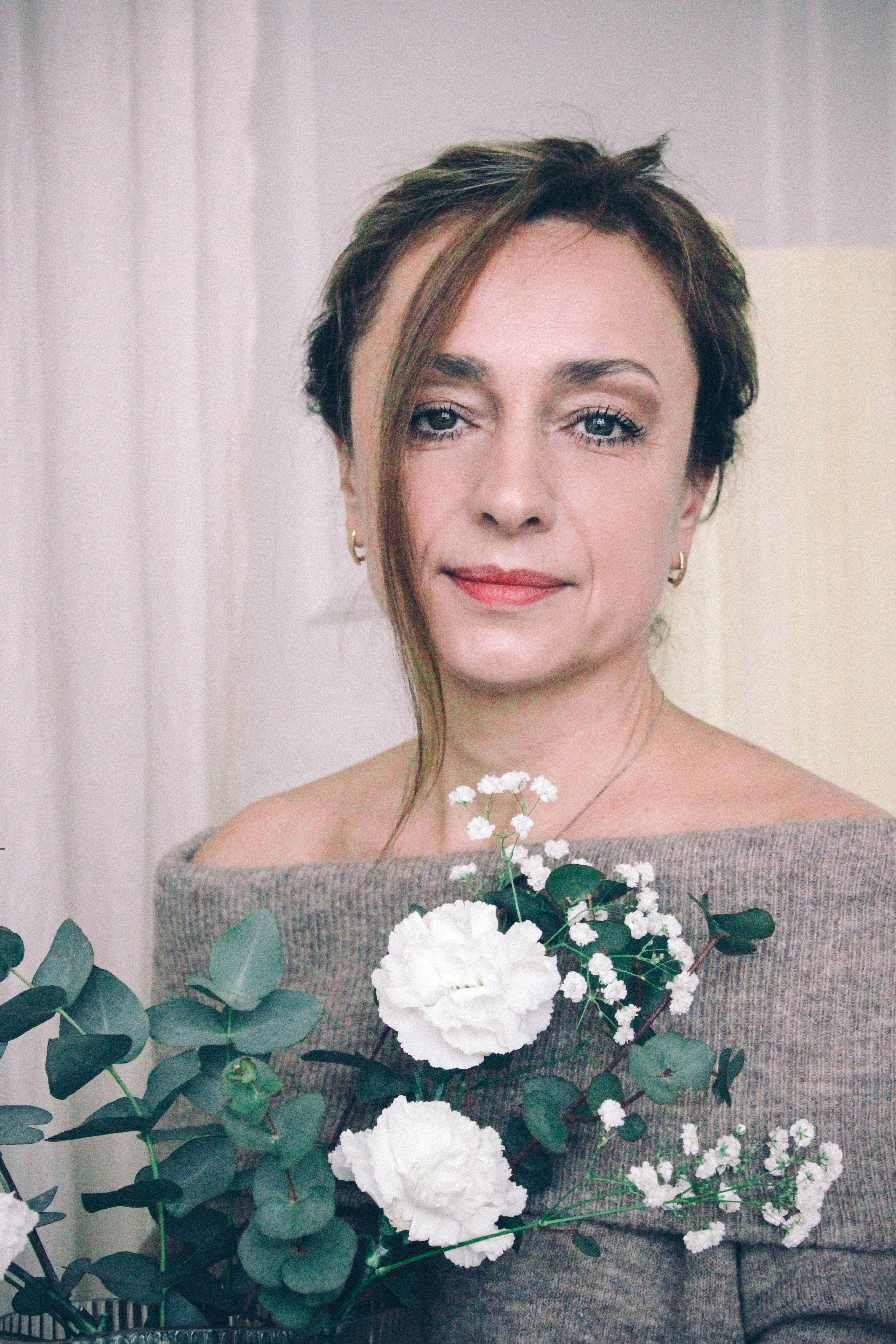 Portrait of a woman holding a floral bouquet, capturing elegance and serenity indoors.