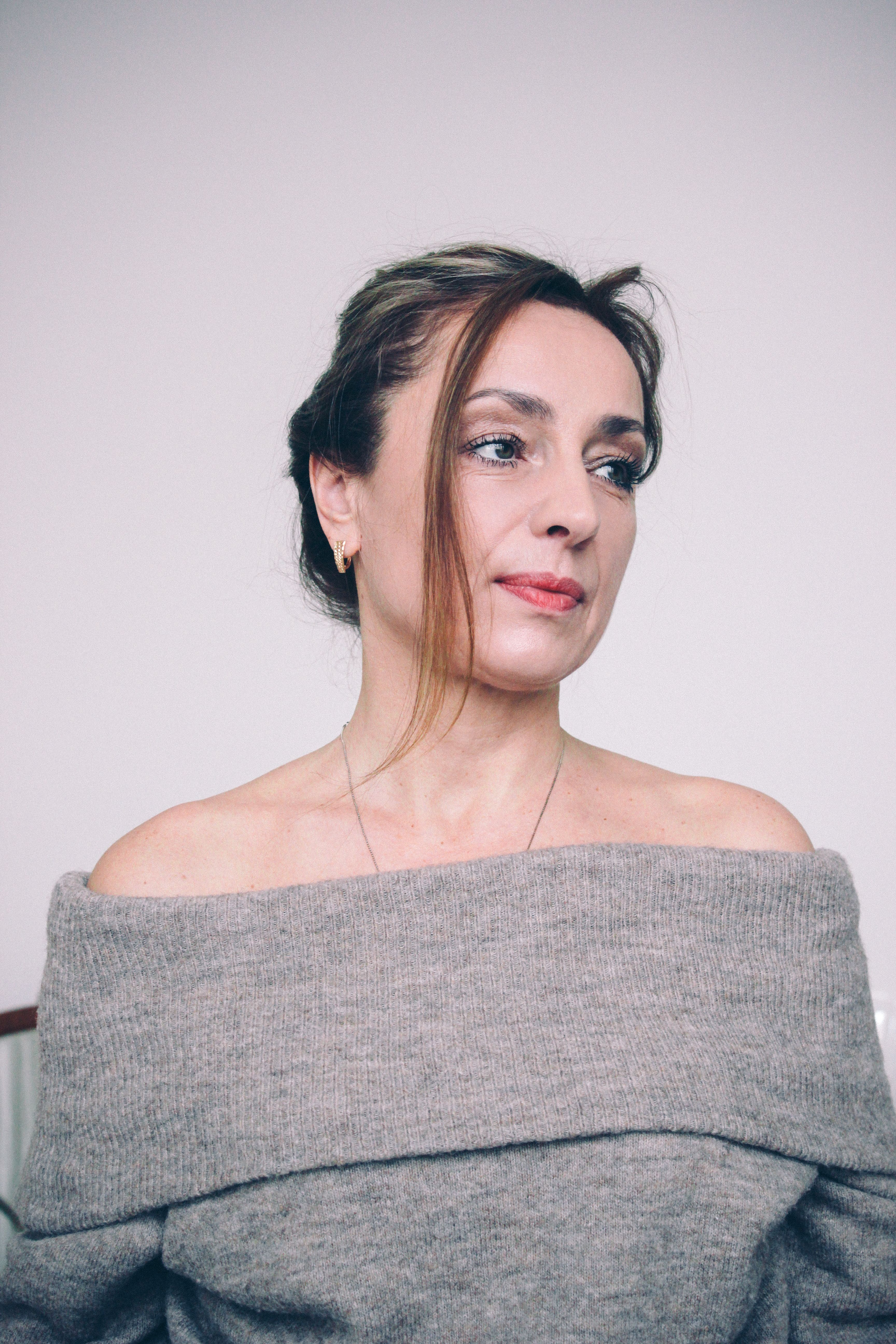 Portrait of a woman in an off shoulder sweater, exuding elegance and style.