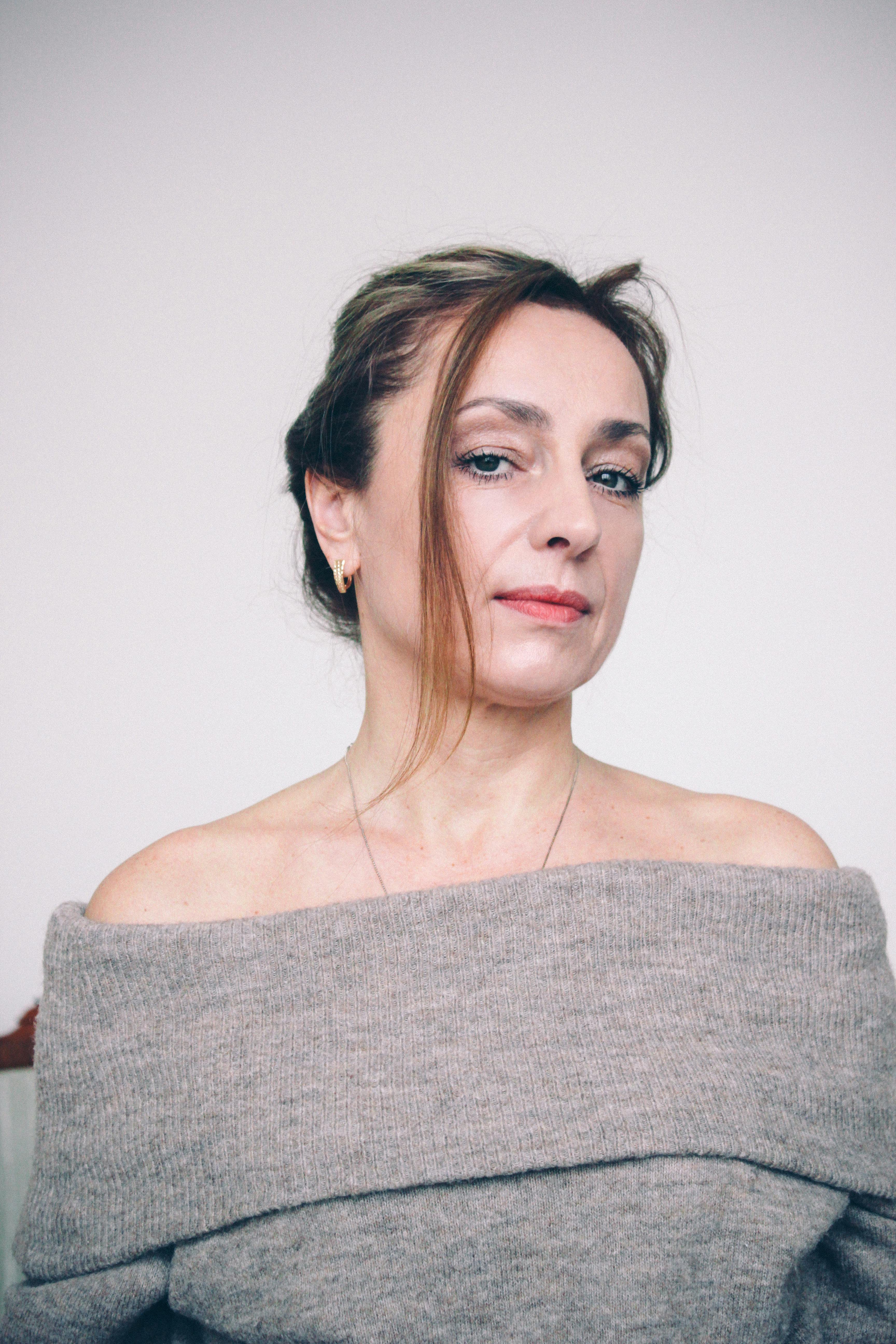 Portrait of a confident woman in an off-shoulder sweater, subtle and natural look.