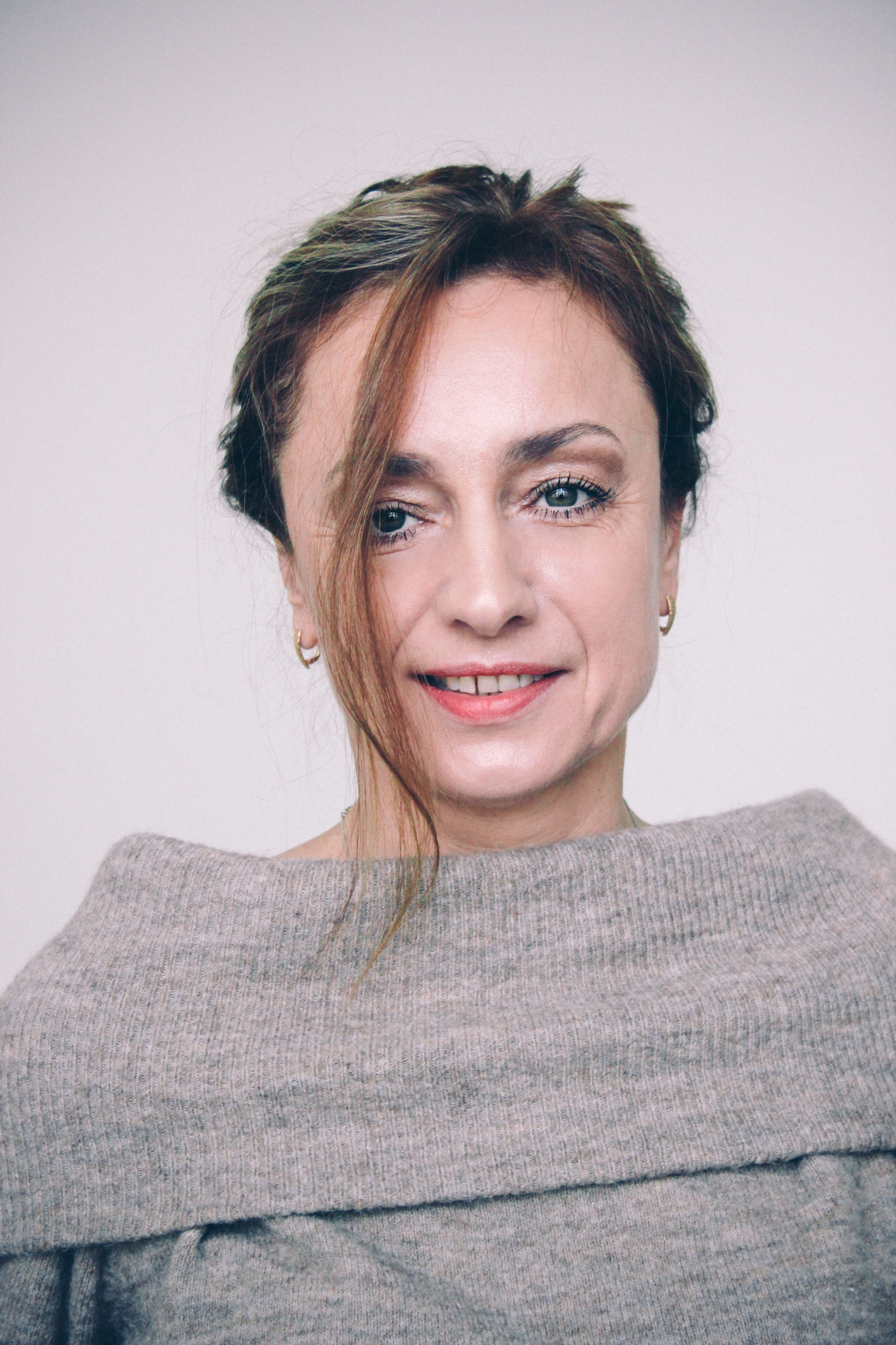 Portrait of a smiling woman wearing a gray top. Captured in Warsaw, Poland.